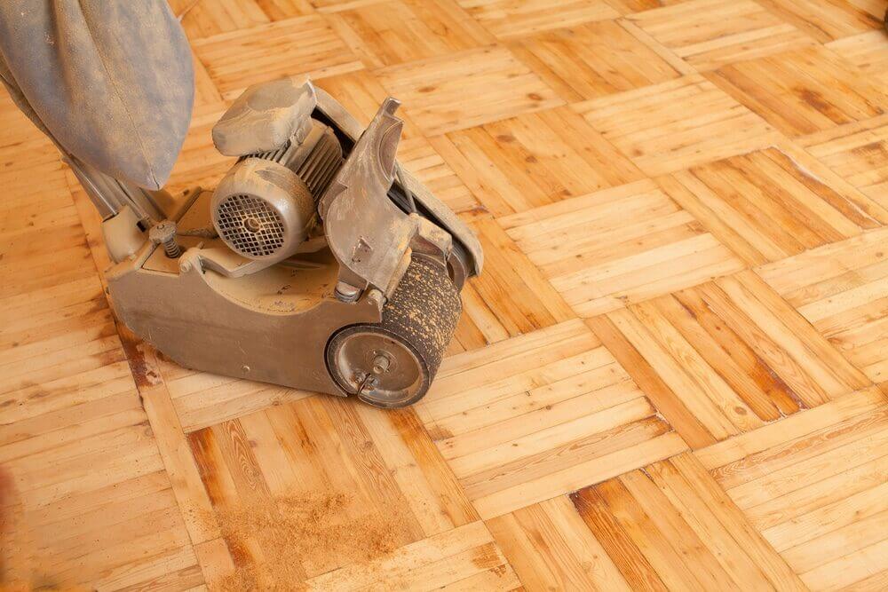 Professional floor sander machine smoothing out a timber parquetry floor.