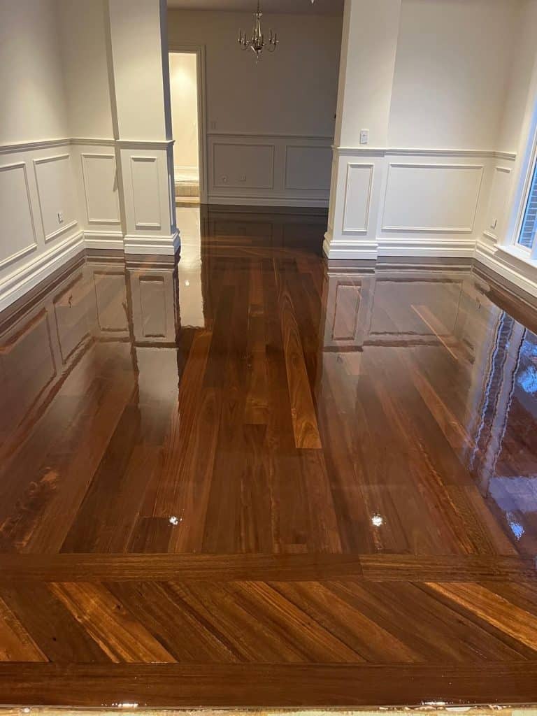 Deep brown timber floor with a high-gloss finish reflecting white wainscoted walls.