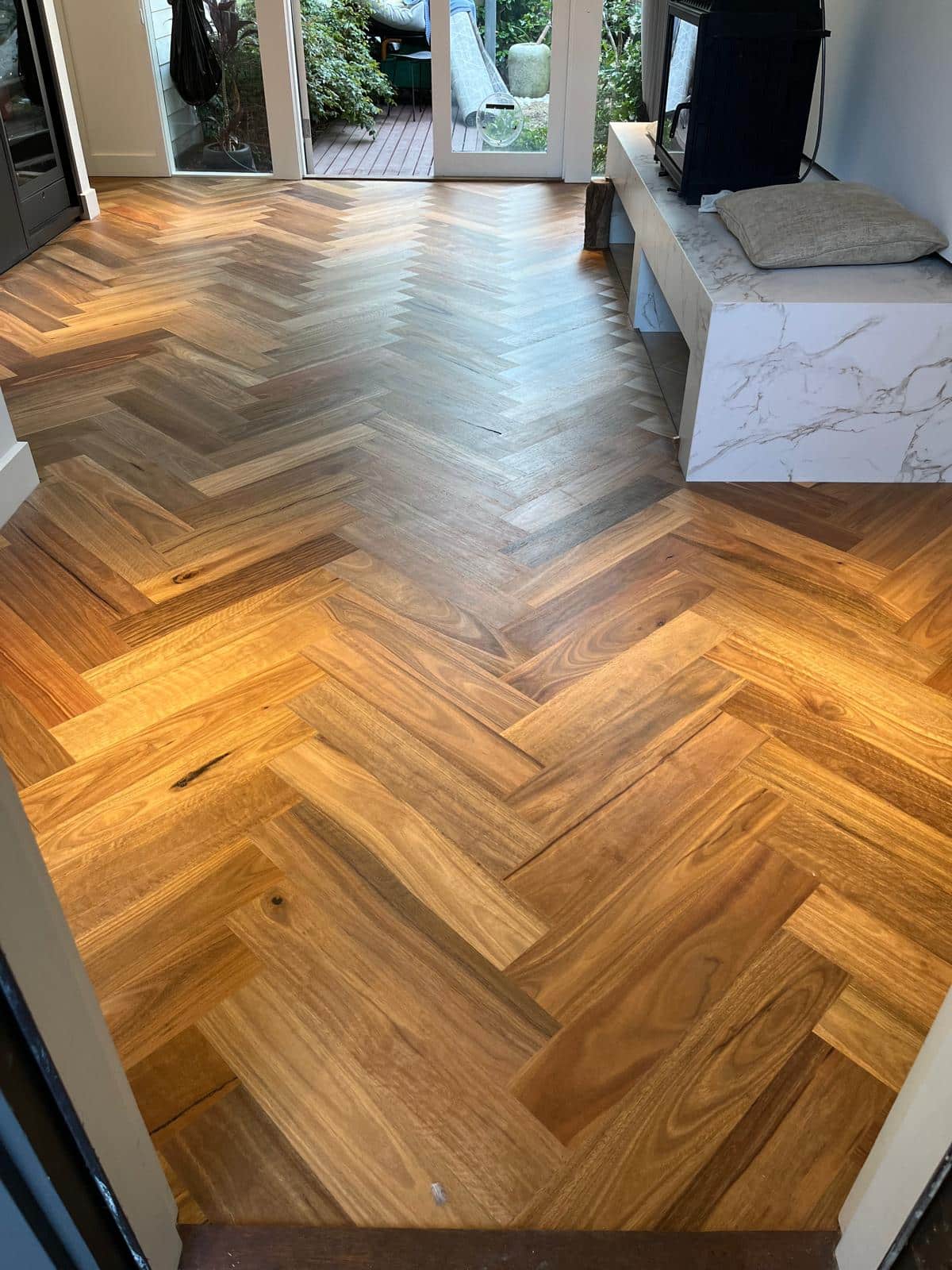 Newly refinished timber floor featuring a classic herringbone pattern in a bright living area.