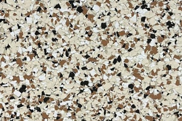 Desert Earth Epoxy Flake Flooring Close-up view of epoxy flooring with a desert earth color palette of beige, brown, white, and black flakes.